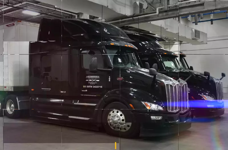 Touring Transportation’s black Peterbilt semi trucks in a loading bay